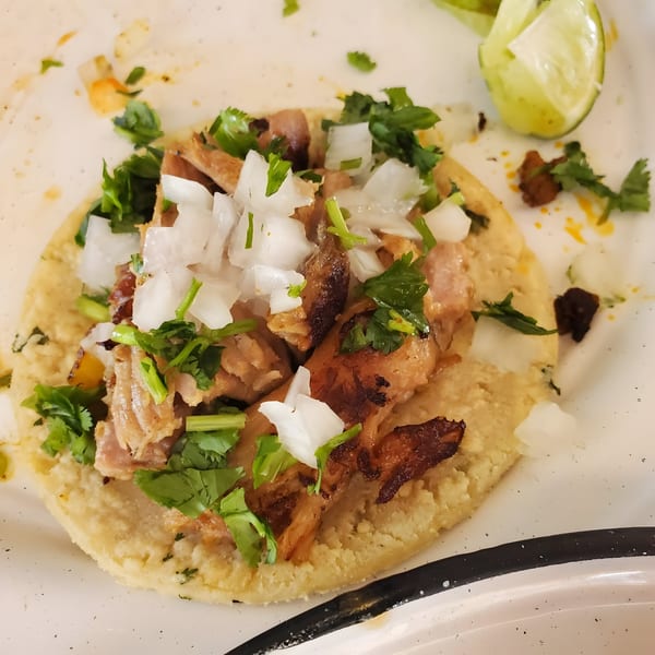 Machete Taqueria's carnitas taco with onions and cilantro, served with a lime wedge.