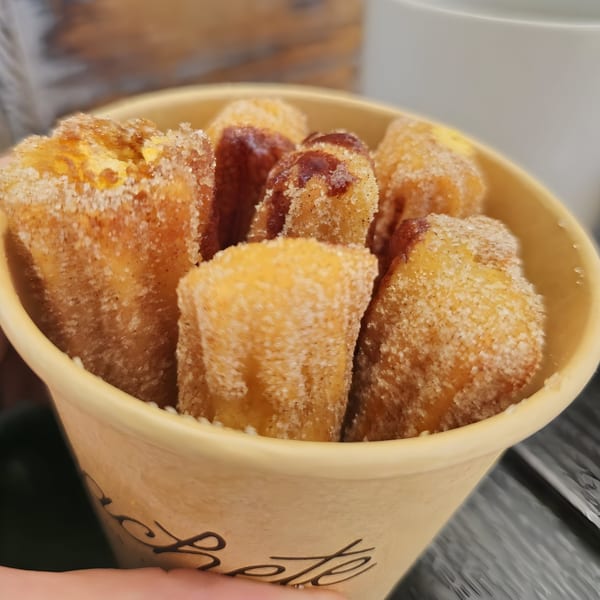 Close-up of Machete Taqueria's churros, dusted with sugar and cinnamon, served in a branded cup.